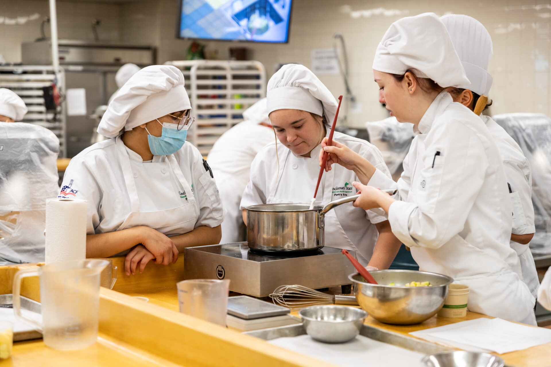 three pastry chefs examining a pot, pastry arts, pastry school, pastry chef