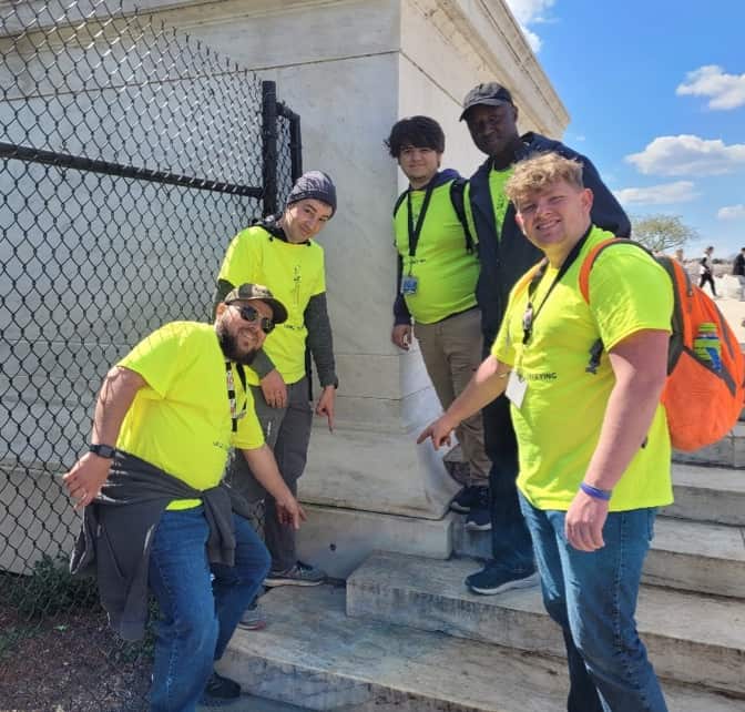The team points to the surveying boundary stone at the Jefferson Memorial