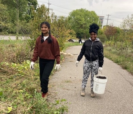 Two students clearing debris during Oct. 2023 workday for Mill Creek Alliance