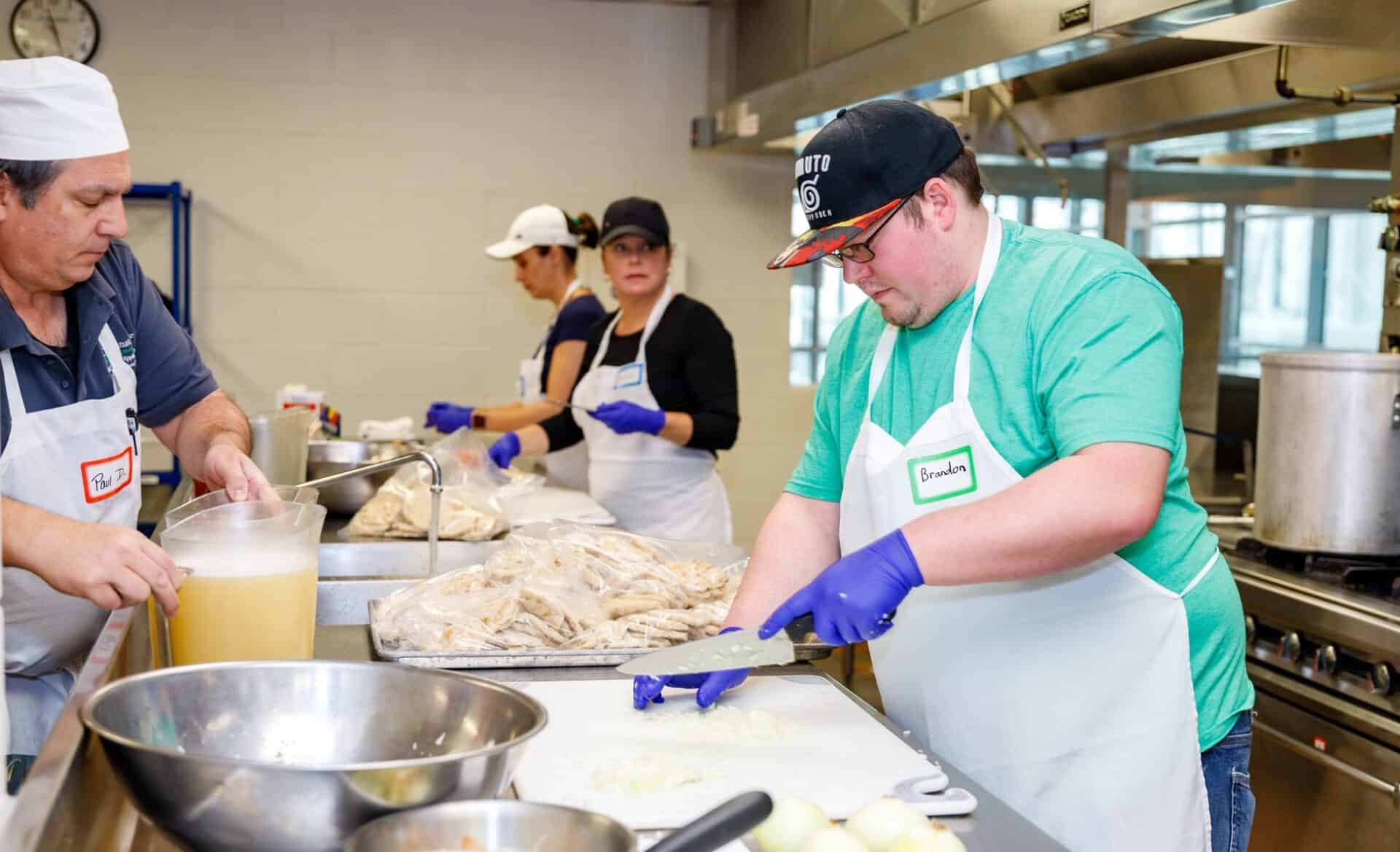 Student Brandon Brinkman and faculty members Wednesday Oster and Donna Von Deylen working in the kitchen