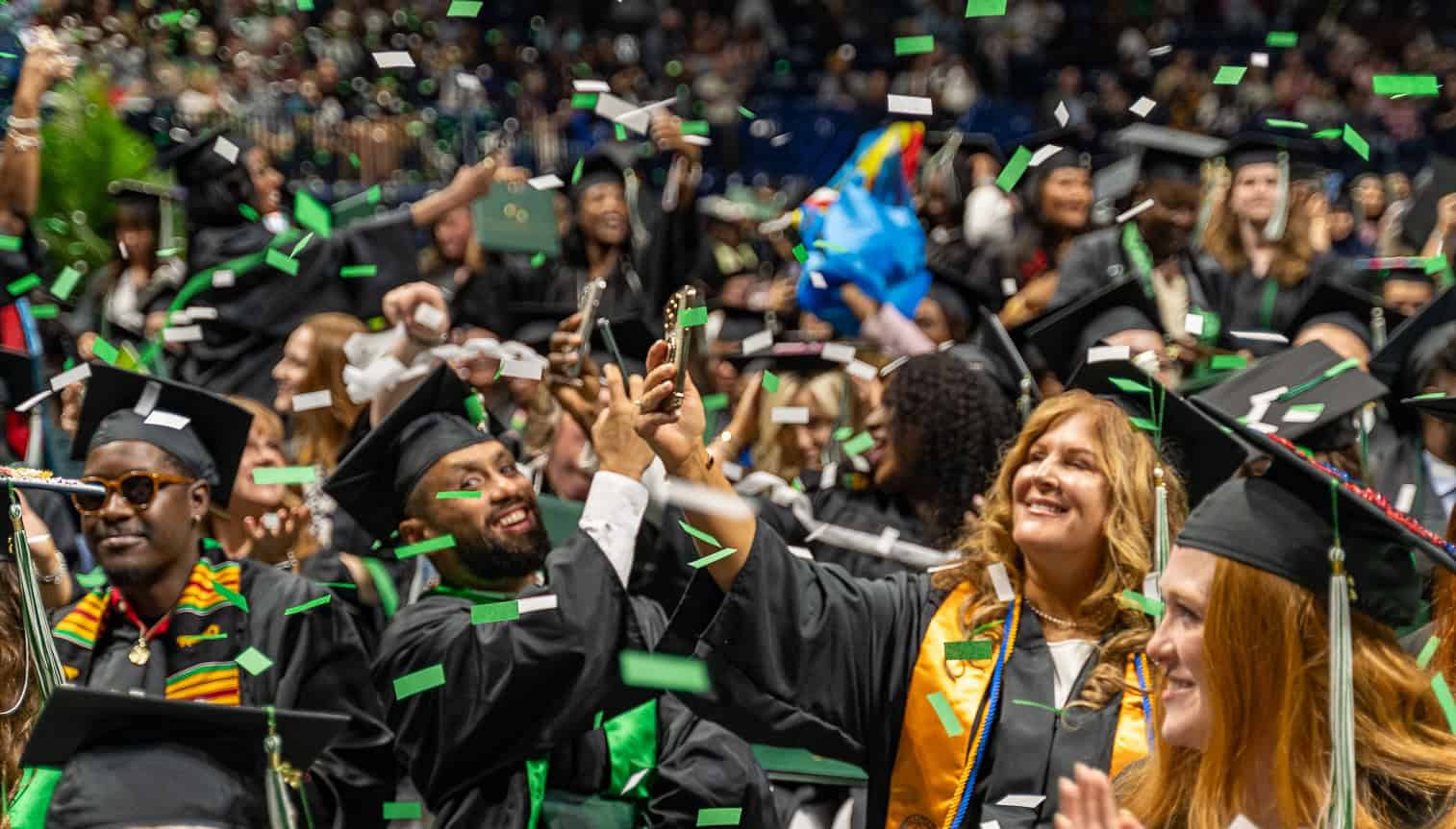 Graduates celebrate while confetti falls at the end of the Commencement ceremony