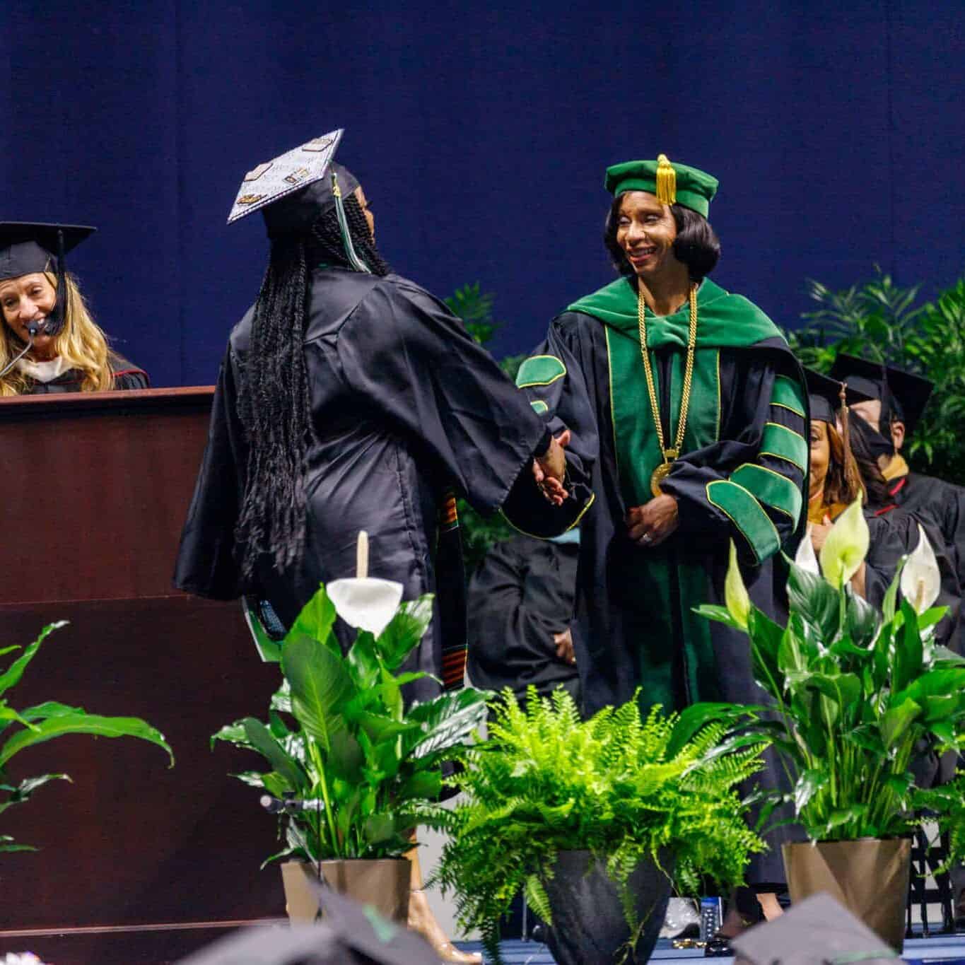 dr posey shaking a students hand at commencement